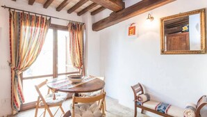 Una habitación con techo de madera, una mesa redonda con sillas, un banco y un espejo en la pared.