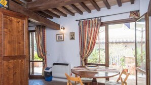 Un comedor rústico con una mesa redonda, sillas de madera y vistas a través de amplias ventanas.