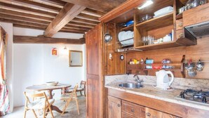 Una cocina rústica con armarios de madera, un lavamanos y un comedor con mesa y sillas.