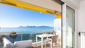 Een balkon met een tafel en stoelen, een bank en uitzicht op zee en bergen.