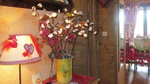 Un intérieur en bois agrémenté d’une lampe, d’un vase décoratif avec des fleurs et d’une petite figurine de cerf posée sur une table.