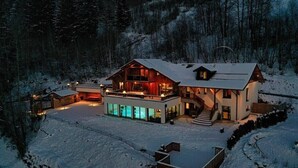 Un grand chalet à plusieurs étages, doté d’un balcon imposant et surplombant un paysage enneigé.