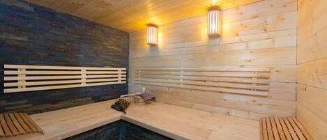 Una sauna con bancos de madera, paredes de piedra y dos luces fijadas a la pared.