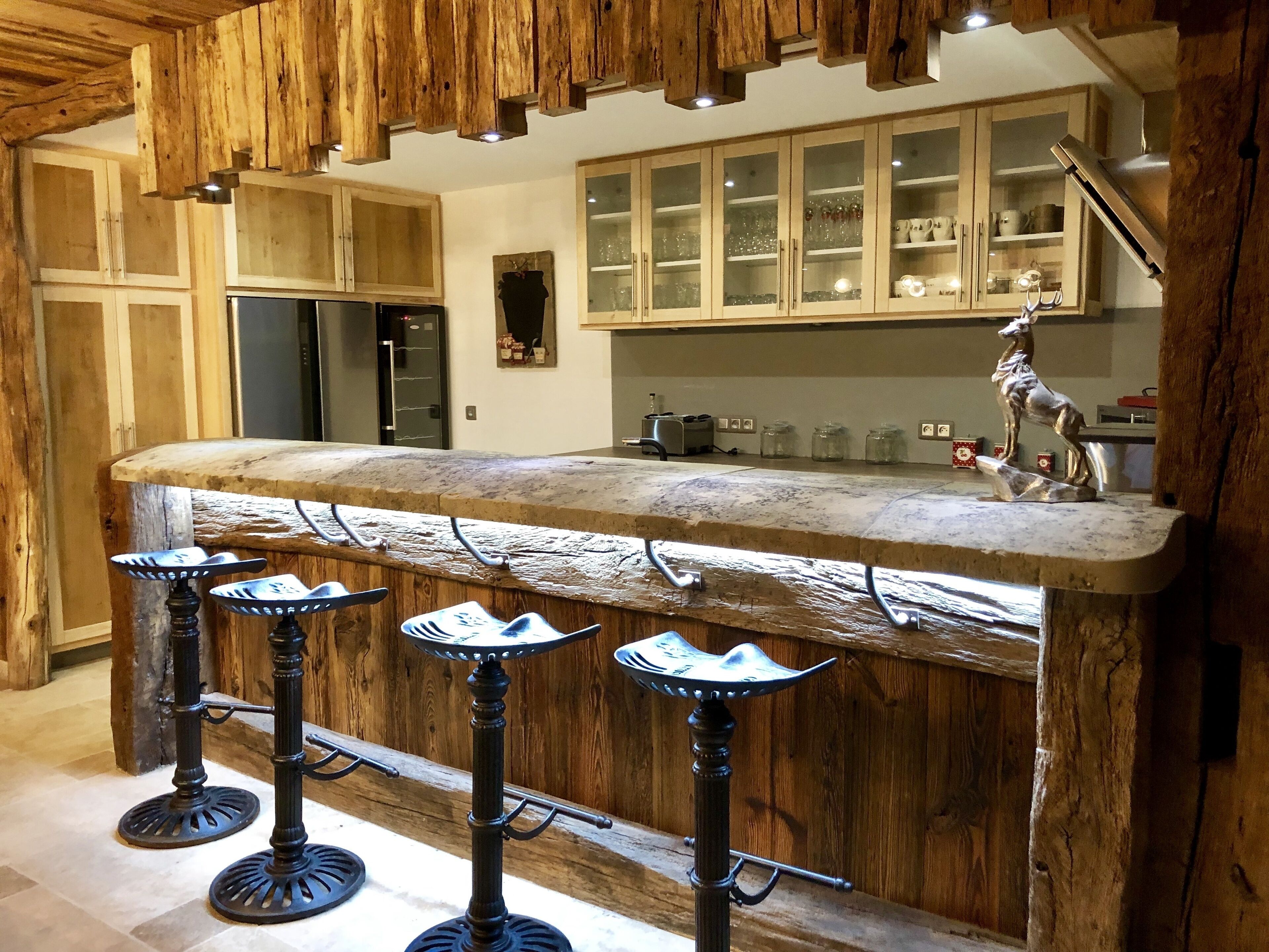 A rustic kitchen with wooden cabinets, a marble island with bar stools, and a decorative horse statue.