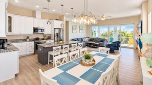 Una cocina moderna con armarios blancos, una isla central y una zona de comedor con manteles individuales azules.