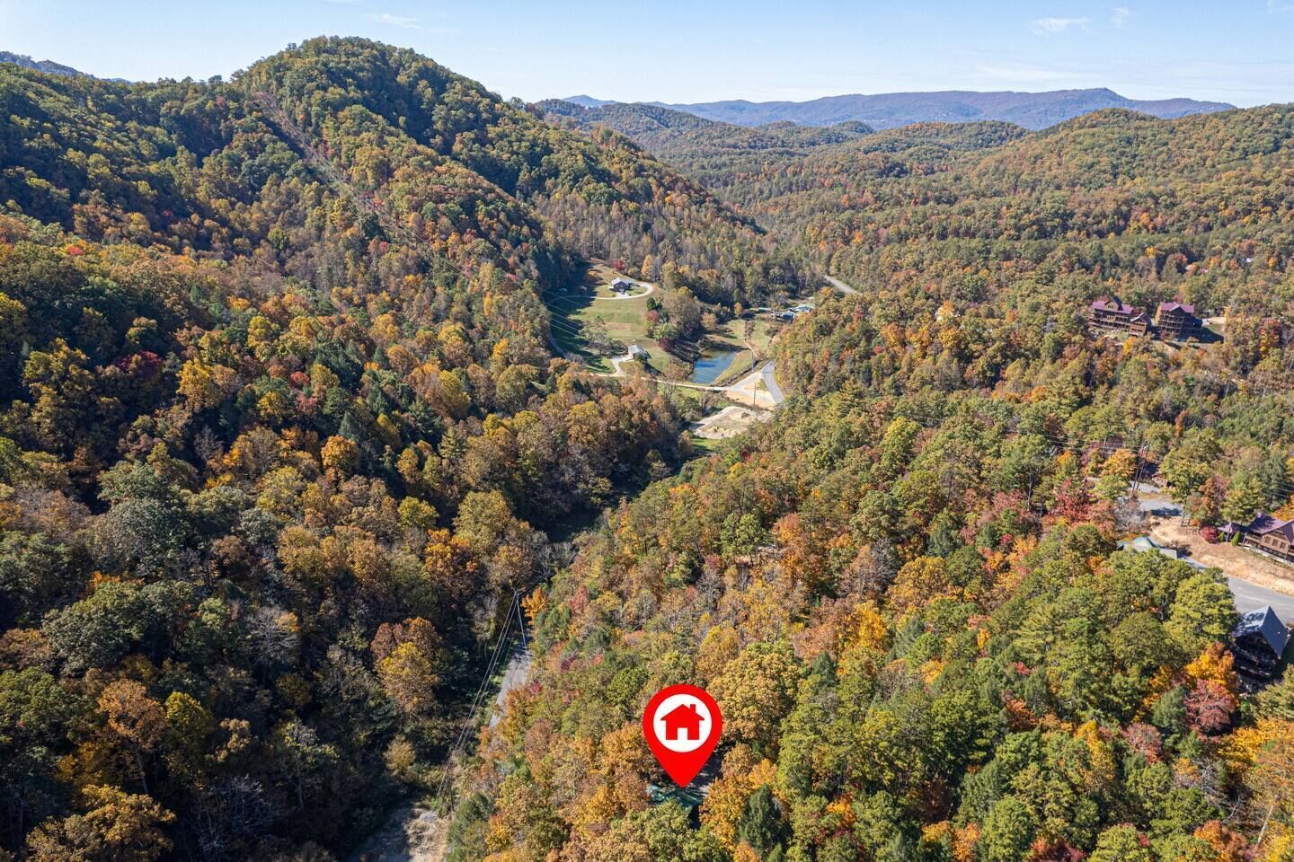 An aerial view of a valley with a river, surrounded by dense forest and hills.