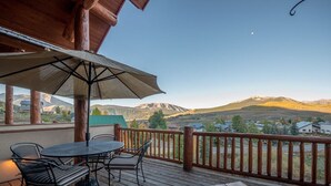 A wooden deck with a table and chairs, an umbrella, and a view of mountains. - Hawks Nest Townhome | 3 Bedroom | Mtn Views | Gas Grill | Gas Fireplace (Mt. Crested Butte)