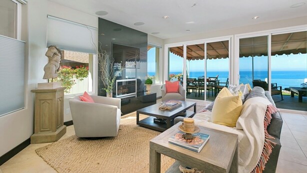 A spacious living room with a large window overlooking the sea, a fireplace, and a comfortable seating area. - OCEANFRONT! 3 DISTINCT SUITES!
 JACUZZI & BBQ! (Encinitas)
