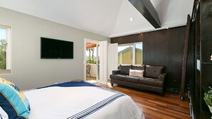 A bedroom with a large bed, a dark-colored sofa, a television mounted on the wall, and a wooden floor. - OCEANFRONT! 3 DISTINCT SUITES!
 JACUZZI & BBQ! (Encinitas)