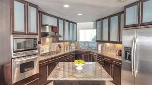 A modern kitchen with dark wooden cabinets, stainless steel appliances, and a granite countertop. - OCEANFRONT! 3 DISTINCT SUITES!
 JACUZZI & BBQ! (Encinitas)