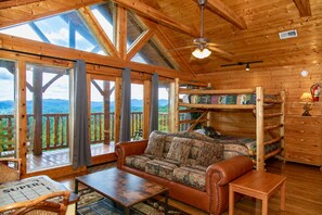 A cabin with a wooden interior, a sofa, a table, and a bunk bed.