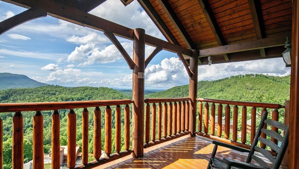Une terrasse en bois dotée d’une rambarde, qui offre une vue sur un paysage montagneux.