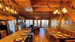 L’intérieur d’un chalet en bois, avec une longue table à manger, des bancs en bois et une cheminée en pierre.