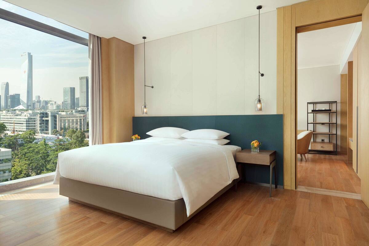 Een moderne hotelkamer met een groot bed, een nachtkastje, een bureau en uitzicht op de stadshemel.