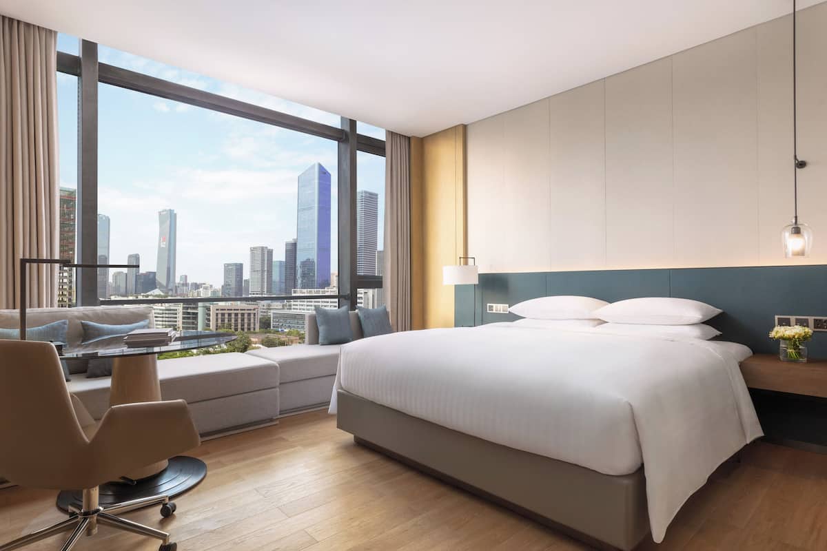 Een moderne hotelkamer met een groot bed, een bureau en uitzicht op de stadshemel.