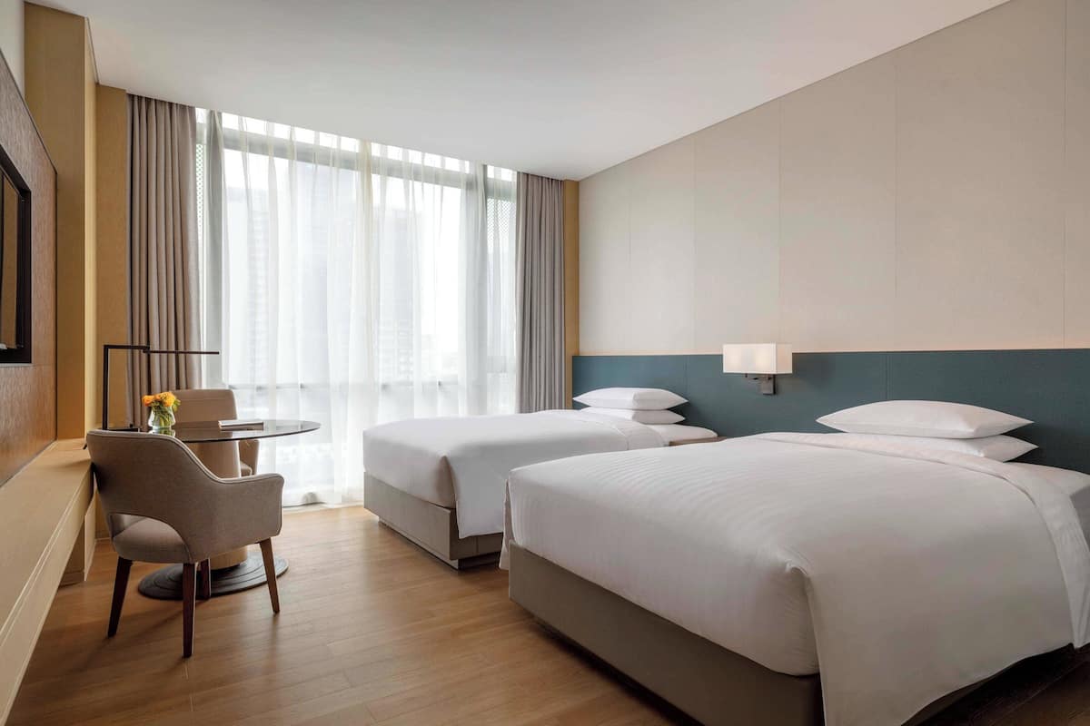 Een hotelkamer met twee bedden, een bureau en een stoel.