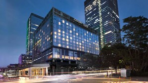 Un hotel de varios pisos con un llamativo letrero 'Courtyard', que cuenta con una fachada de vidrio moderna y un área de entrada bien iluminada.