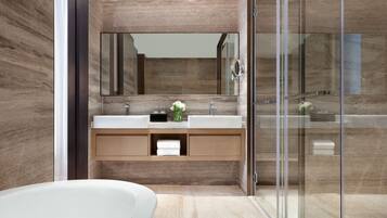 A modern bathroom with a glass shower enclosure, a large mirror, and a white bathtub.