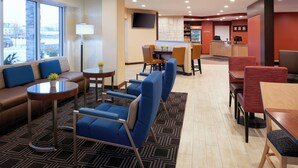 A hotel lobby with seating areas, a reception desk, and a bar. - TownePlace Suites by Marriott Jackson (Jackson)
