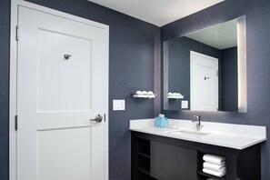 A modern bathroom with a white door, a large mirror, a white sink, and a towel rack. - Residence Inn by Marriott Toronto Mississauga West (Mississauga)