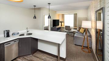Une chambre d’hôtel moderne équipée d’un coin cuisine, d’un canapé, d’une table à manger et d’un téléviseur.