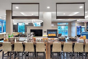 A modern dining area with a large wooden table, multiple chairs, a fireplace, and a bar area with a refrigerator. - Residence Inn by Marriott Toronto Mississauga West (Mississauga)