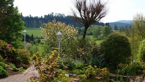 A garden with a paved path, various flowering plants, and a lamp post. - Waldhotel (Brilon)