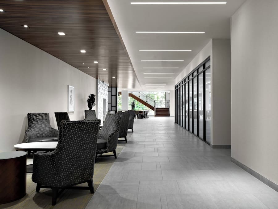 En modern hall med sittplatser, en trappa och stora fönster.