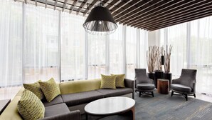 A modern lounge area with a sofa, chairs, a coffee table, and a hanging light fixture.