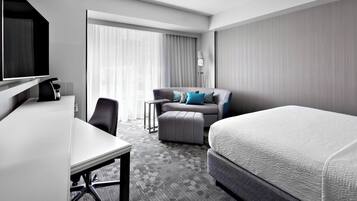 Una habitación de hotel moderna con una cama grande, un escritorio, un sofá y un televisor.