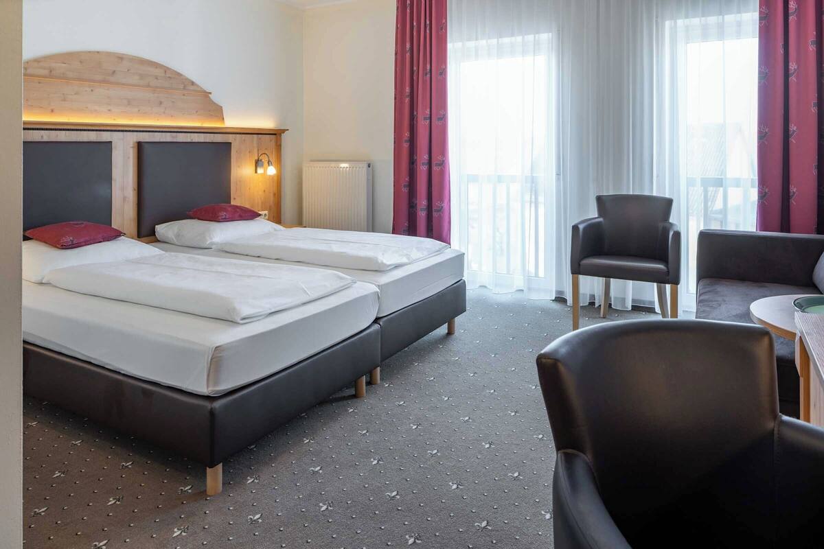 Une chambre d’hôtel avec deux lits, une chaise, une table et une vue sur l’extérieur.