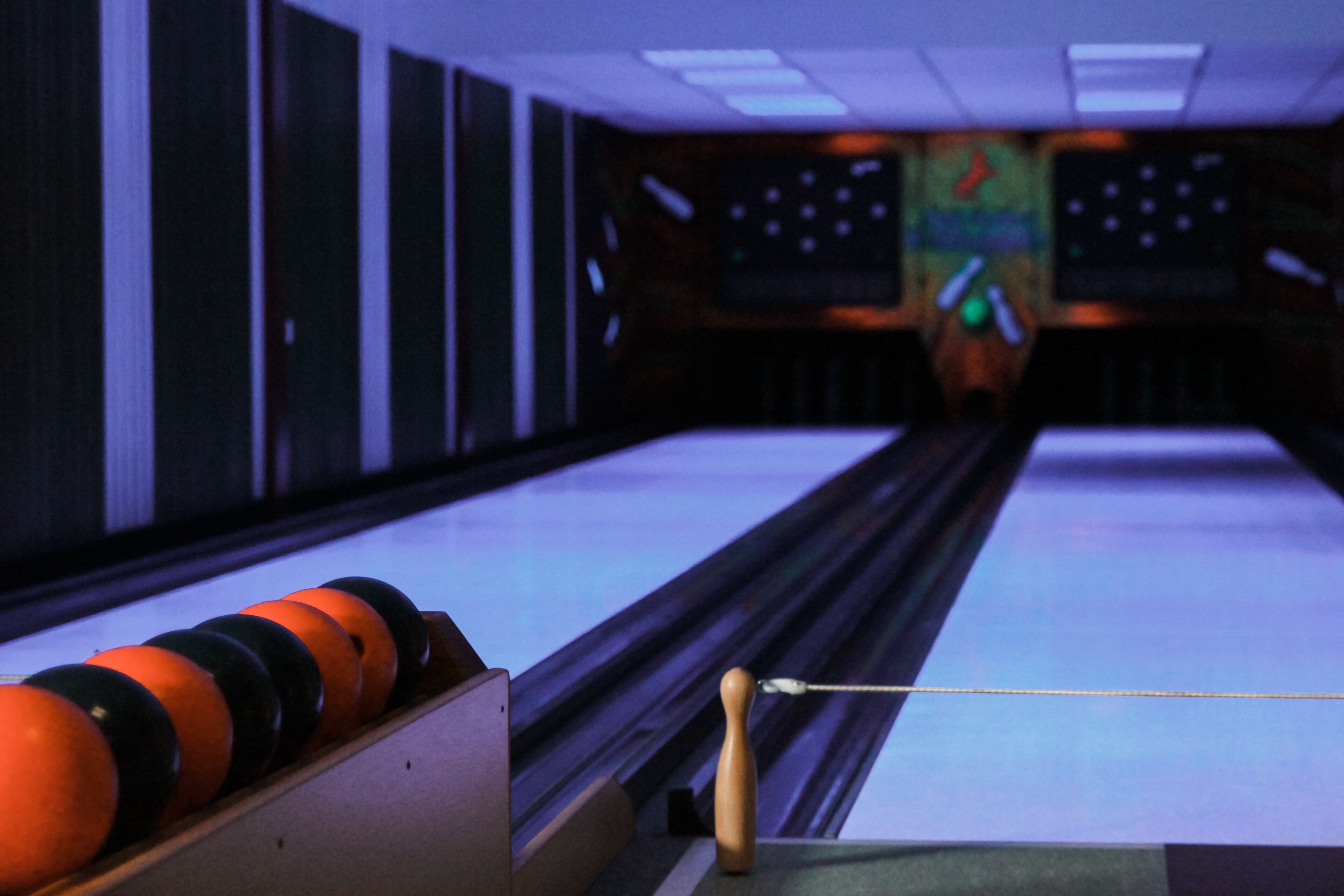 Une salle de bowling avec des pistes, des quilles et un présentoir à boules de bowling.