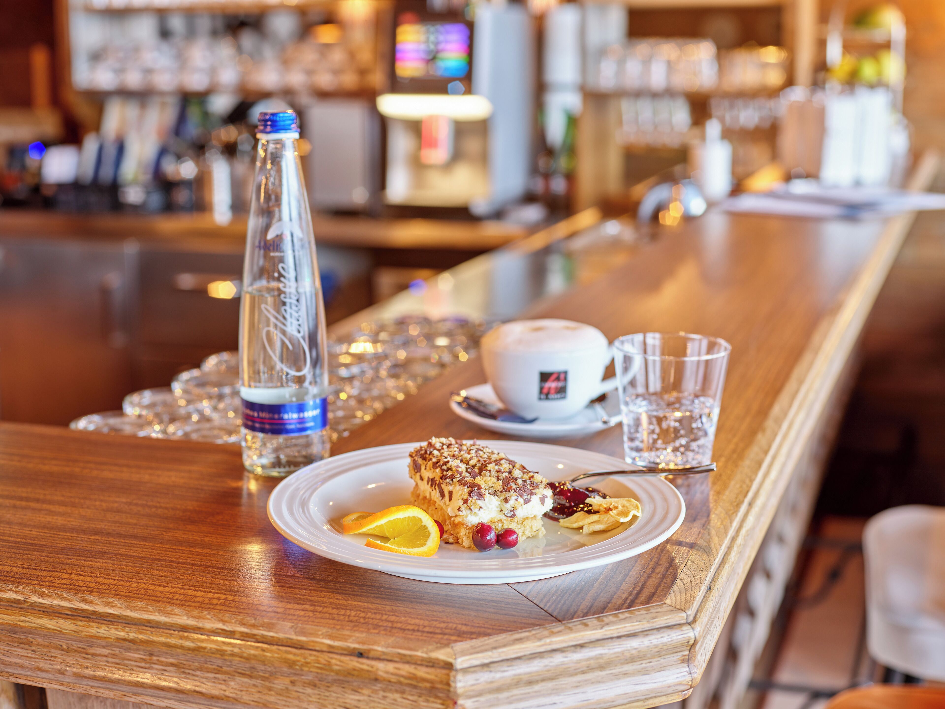 A bar area with a bottle of water, a cup, and a plate with food.