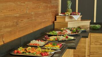 A buffet table with various food items including salads, fruits, and cheeses.