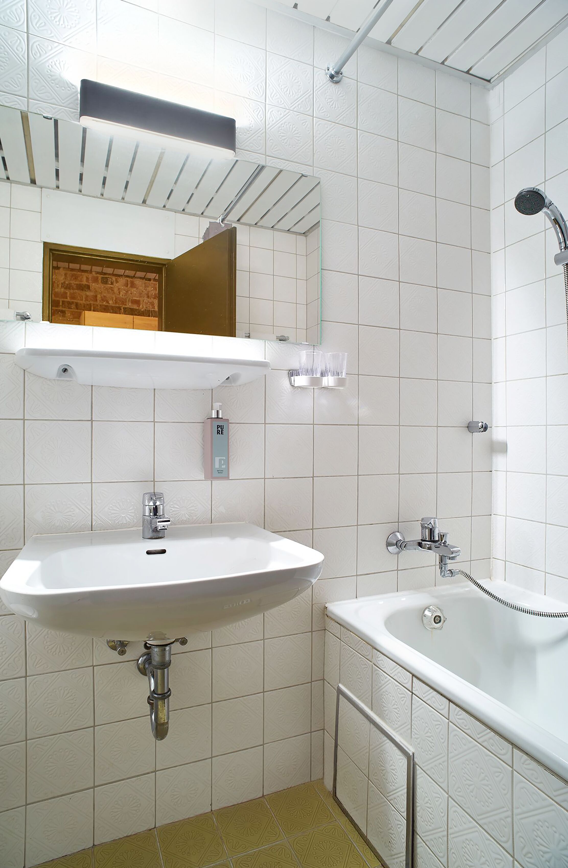 Un baño con lavamanos, espejo y bañera.