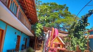 Un cortile con un vialetto in pietra, una recinzione in legno e una piccola costruzione in legno decorata con tessuti colorati.
