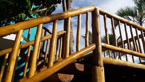 Una scala in legno con corrimano, immersa in una vegetazione tropicale e palme.