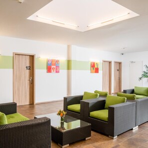 Un hall de hotel con mobiliario de mimbre, una mesa de centro de vidrio y una planta.