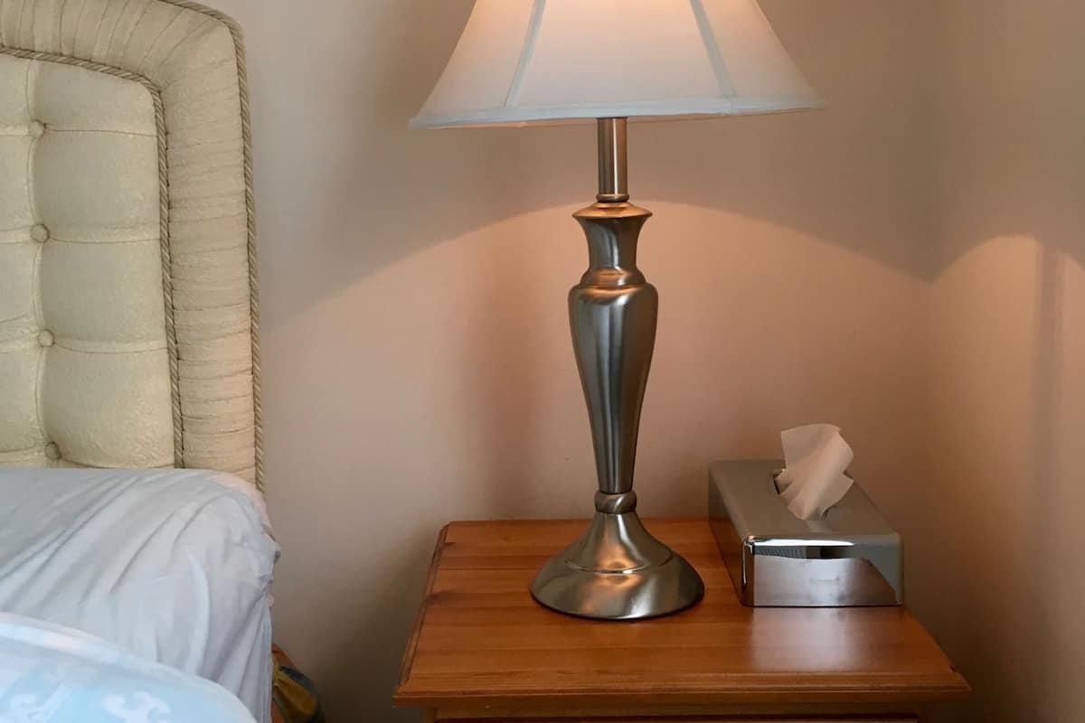 A bedside table with a lamp, a tissue box, and a drawer.