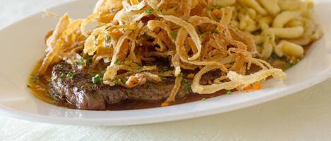 Un plato de carne con cebollas y hierbas aromáticas.