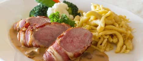 A plate with sliced ham, mushrooms, broccoli, carrots, and macaroni.