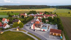 Vista aérea de un pueblo con casas, una calle principal y campos circundantes.