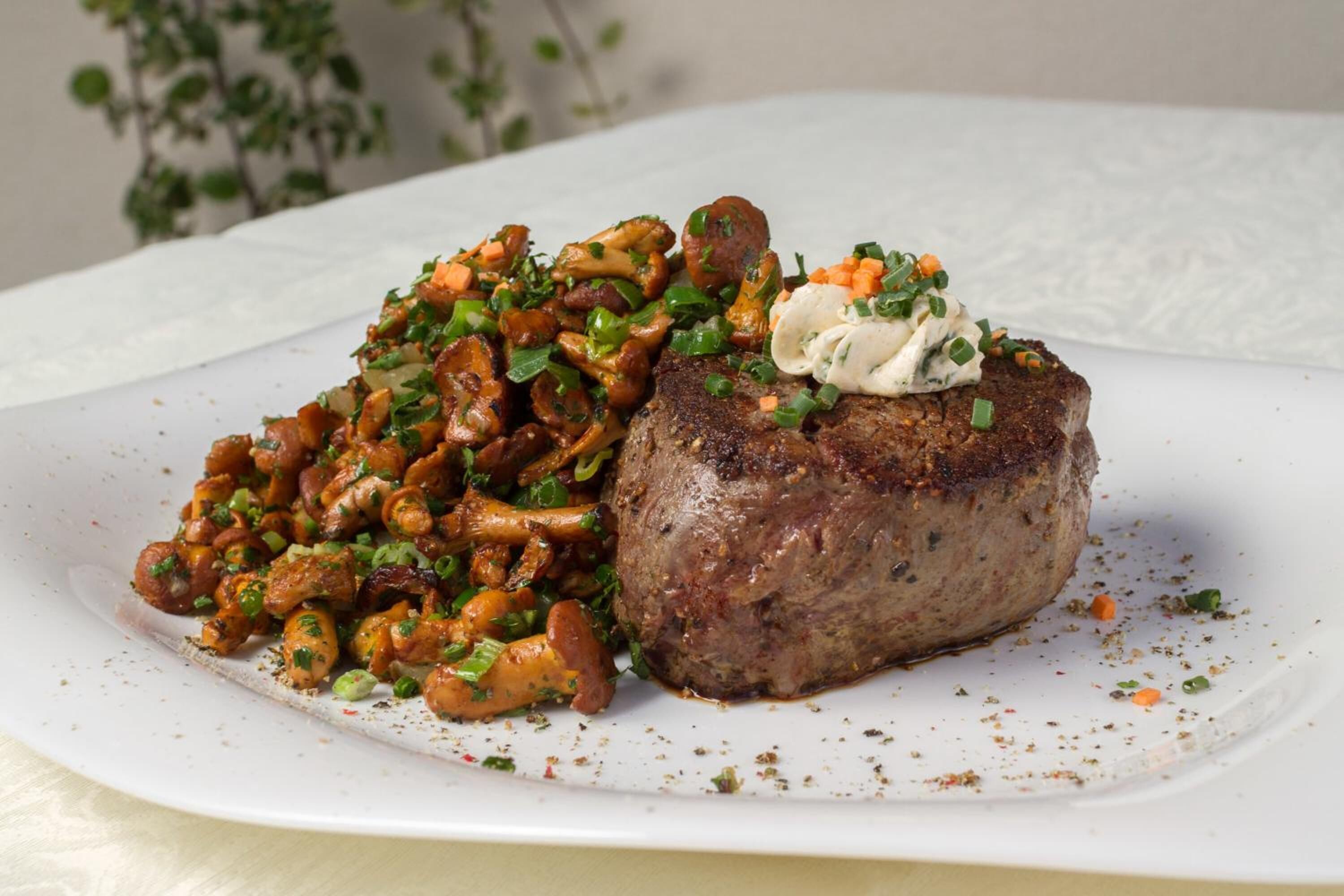 Un piatto con una bistecca e un contorno di funghi saltati e verdure.
