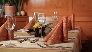 Una mesa de comedor dispuesta con copas de vino, cubiertos y servilletas.