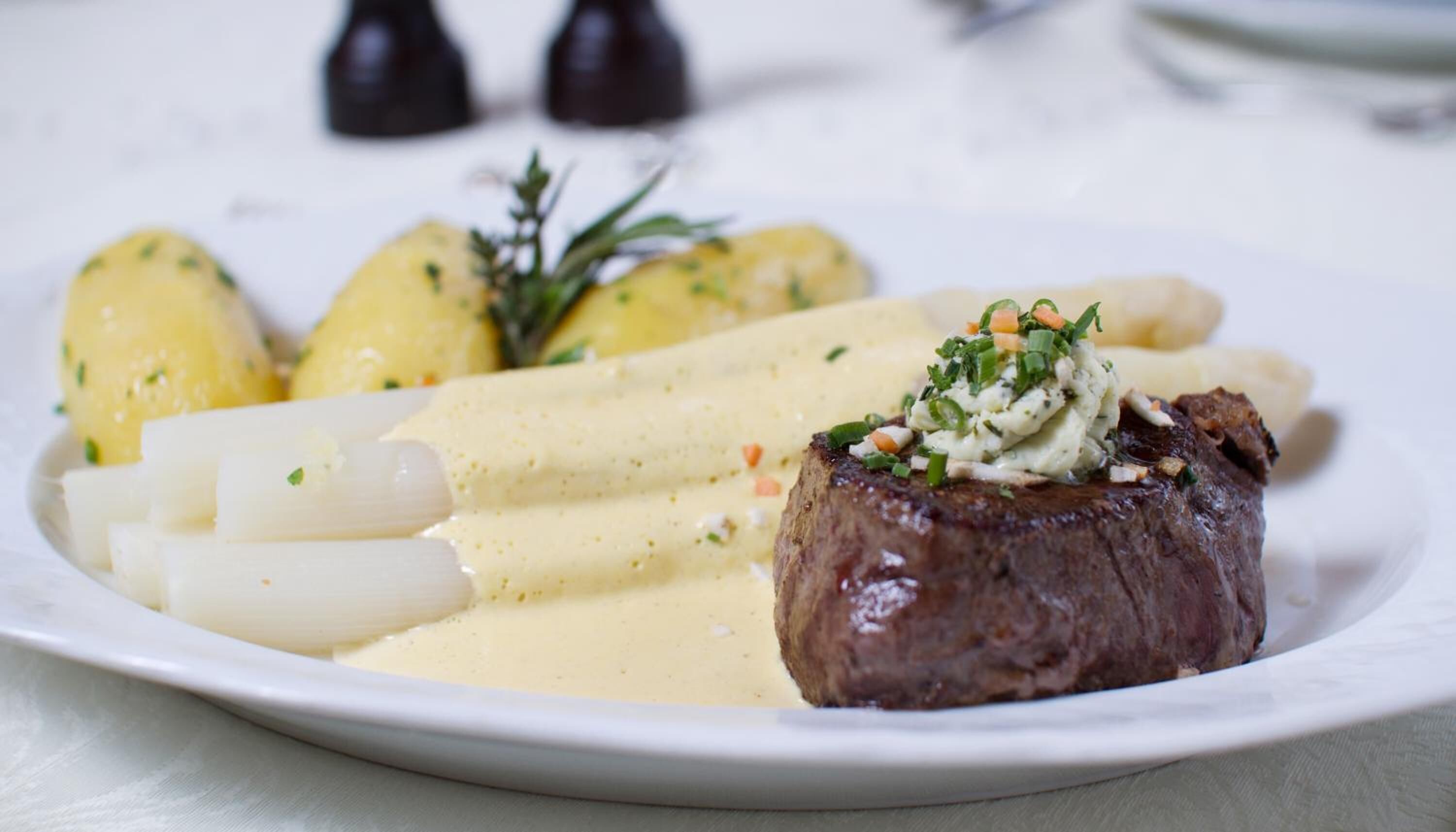 En tallerken med steak, kogte kartofler og asparges.