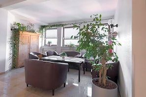 A dining area with a table and chairs, a potted plant, and a wooden cabinet. - Bartholomäus (Zeitlarn)