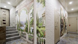 Um corredor com um mural de paisagem, degraus de mármore e uma porta.