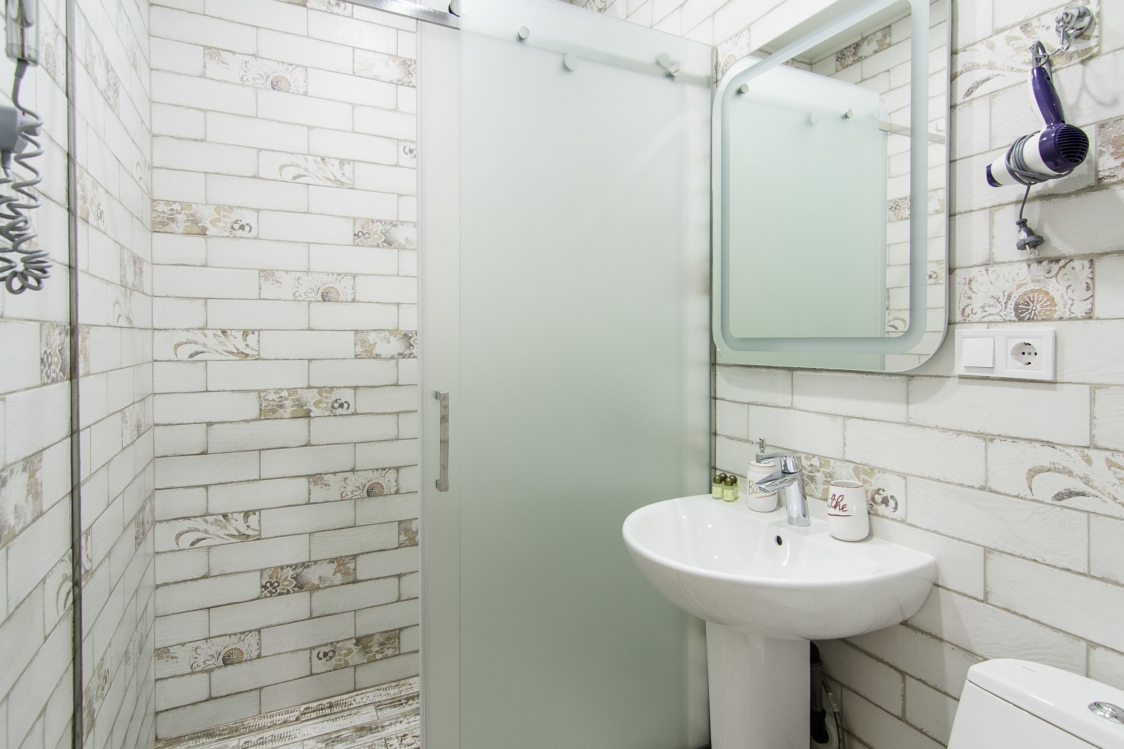 A bathroom with a shower, a sink, and a mirror.