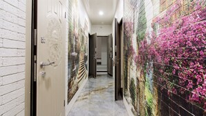Um corredor com paredes em azulejo, chão de mármore e porta com puxador ornamentado.
