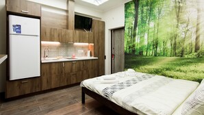 Quarto moderno com claraboia, cama com colcha estampada e vista para uma floresta através de uma janela grande.